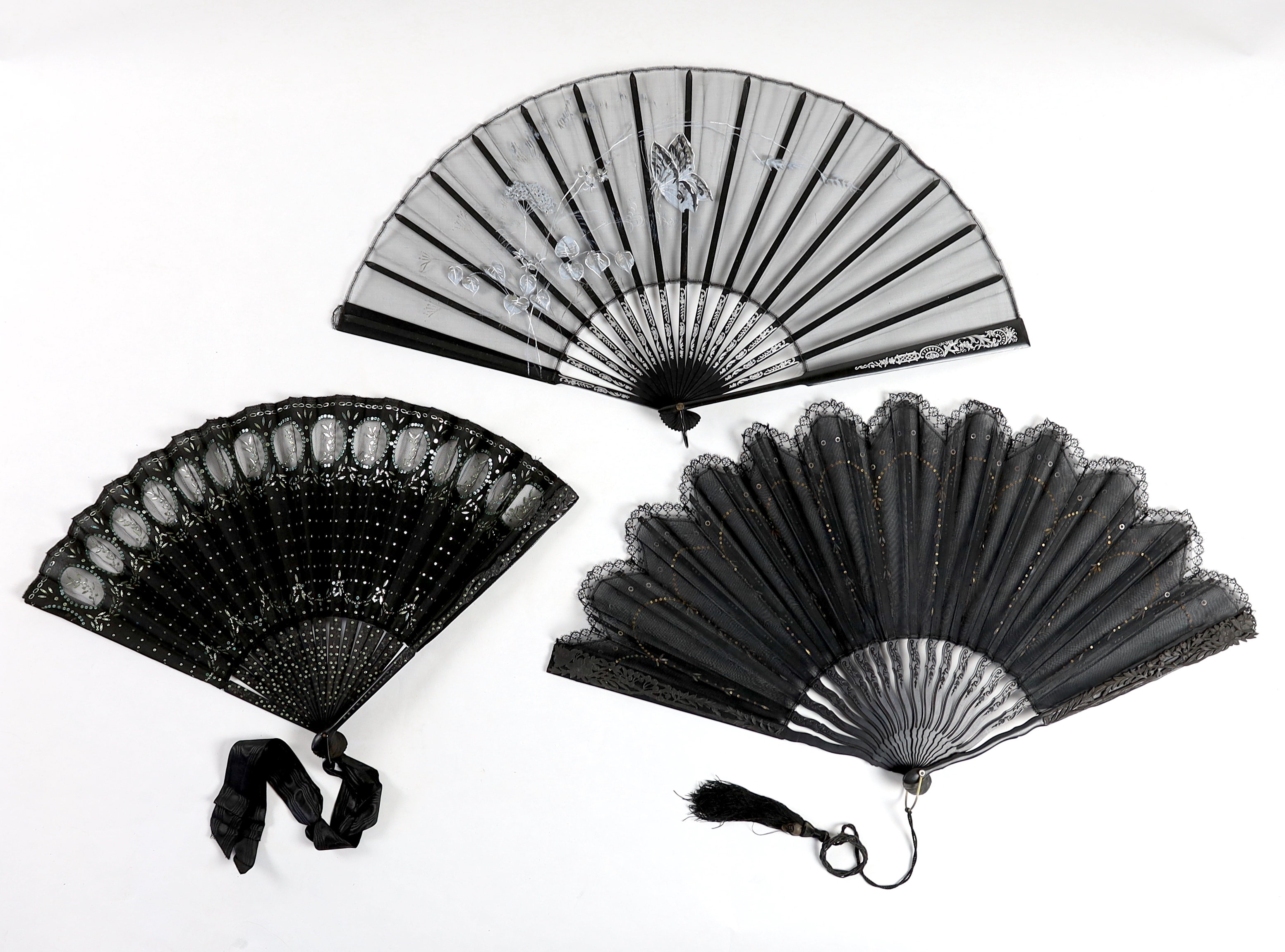 An Edwardian black silk and ornate sequin fan, a similar fan with carved ebony guards and a fine gauze fan with painted sprig and butterfly decoration (3)